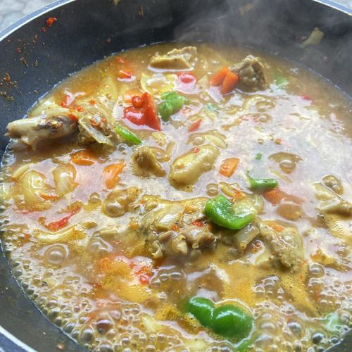 Chicken curry sauce simmering in a pot with peppers and carrots
