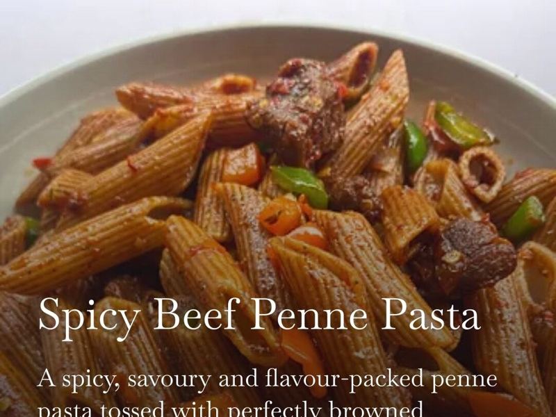 Spicy beef penne pasta tossed with peppers in a bowl