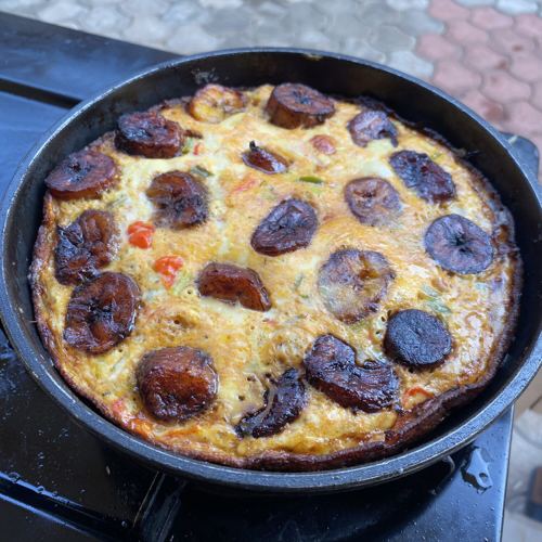 Egg and plantain frittata cooking in a pan